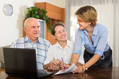 Smiling senior couple answer questions of social worker at home